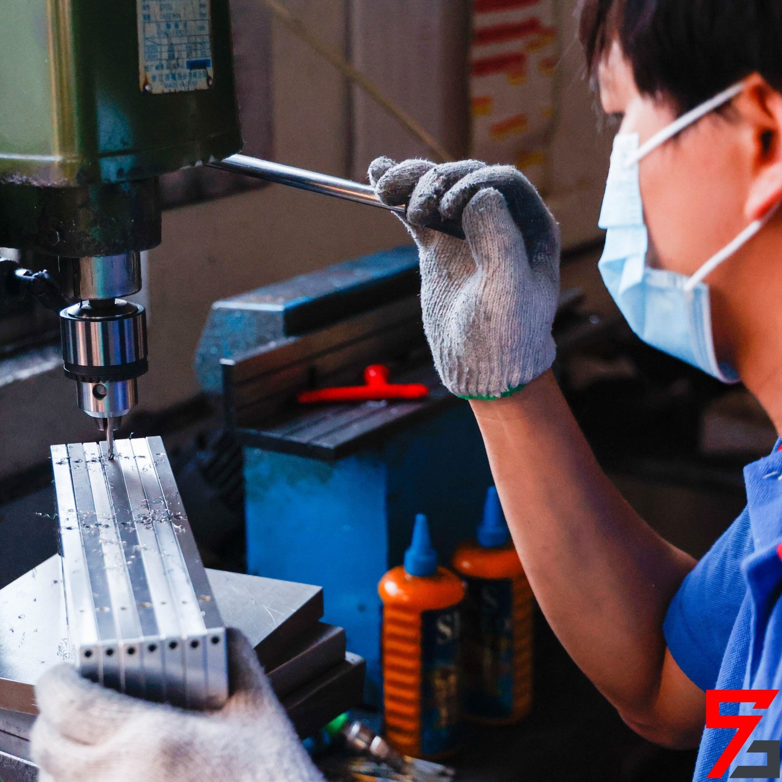 The worker is drilling holes in the parts